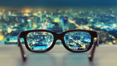 Une paire de lunettes posée sur une table, permettant de voir une ville illuminée la nuit.