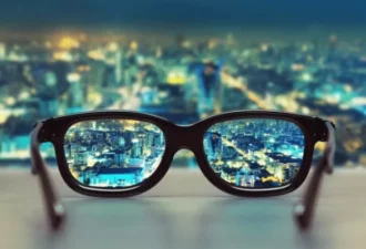 Une paire de lunettes posée sur une table, permettant de voir une ville illuminée la nuit.