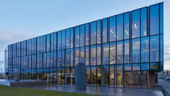 Un grand bâtiment en verre avec de nombreuses fenêtres et une statue devant lui.
