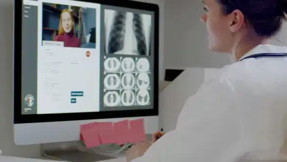 Professionnelle de santé en consultation de téléradiologie, analysant des radiographies thoraciques et des scanners sur un ordinateur lors d'une vidéoconférence.
