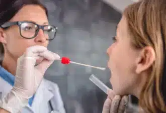 Medecin qui procède un test salivaire sur une patiente de sexe féminin